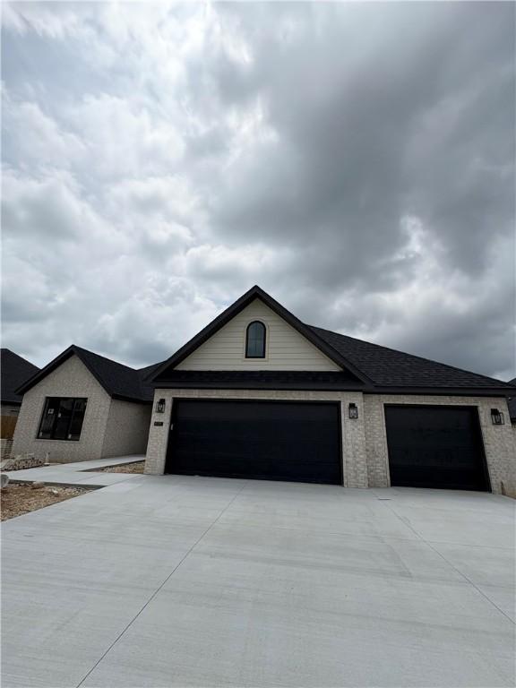 825 Bellagiola, Tontitown, AR 72762 - view of front of house featuring an attached garage, concrete driveway, and brick siding