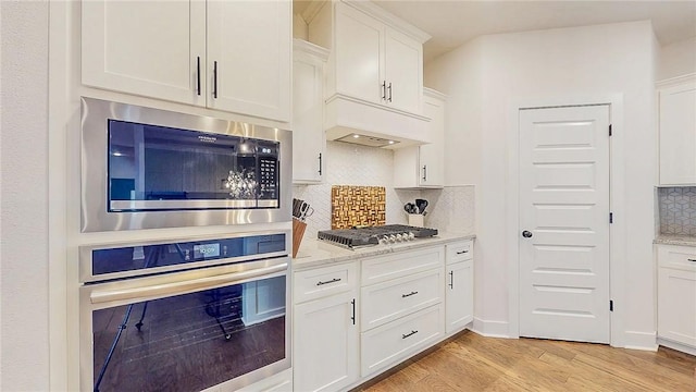 884 Ardiano Ave, Tontitown, AR 72762 - kitchen featuring appliances with stainless steel finishes, light wood-type flooring, white cabinets, tasteful backsplash, and light stone countertops