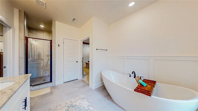 884 Ardiano Ave, Tontitown, AR 72762 - bathroom with a stall shower, a soaking tub, vanity, a closet, and a wainscoted wall