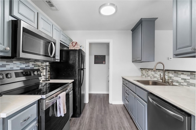 874 Oakwood Ln, Centerton, AR 72719 - kitchen with appliances with stainless steel finishes, gray cabinets, tasteful backsplash, light countertops, and wood finished floors