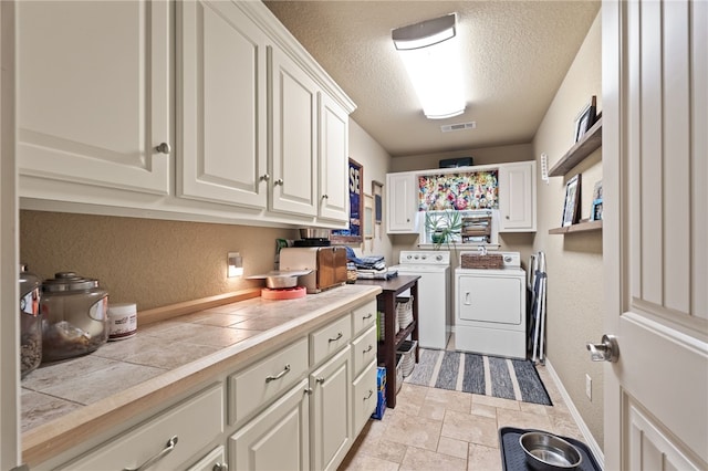 217 Waterfront Cir, Alma, AR 72921 - washroom with washer and dryer, cabinet space, a textured wall, a textured ceiling, and light stone finish flooring