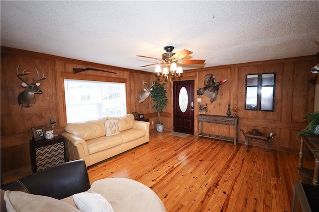 4639 Quail Ct, Harrison, AR 72601 - living area featuring wooden walls, light wood-style flooring, a ceiling fan, and a textured ceiling