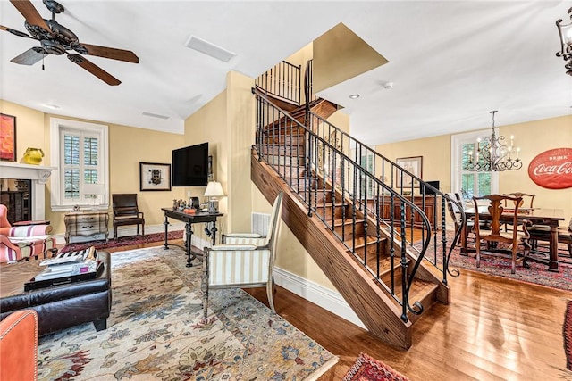 32 Armstrong St, Eureka Springs, AR 72632 - stairway with ceiling fan, wood finished floors, a tiled fireplace, and a chandelier