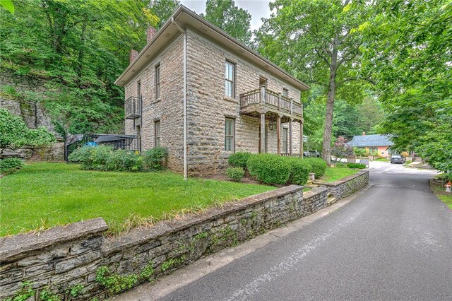 32 Armstrong St, Eureka Springs, AR 72632 - view of front facade featuring a balcony, a chimney, stone siding, and a front yard