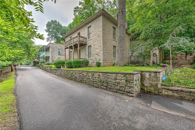 32 Armstrong St, Eureka Springs, AR 72632 - view of front of property featuring a balcony, a chimney, and stone siding