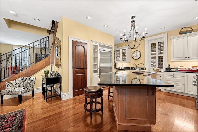 32 Armstrong St, Eureka Springs, AR 72632 - kitchen with a chandelier, a kitchen bar, white cabinetry, wood finished floors, and a center island