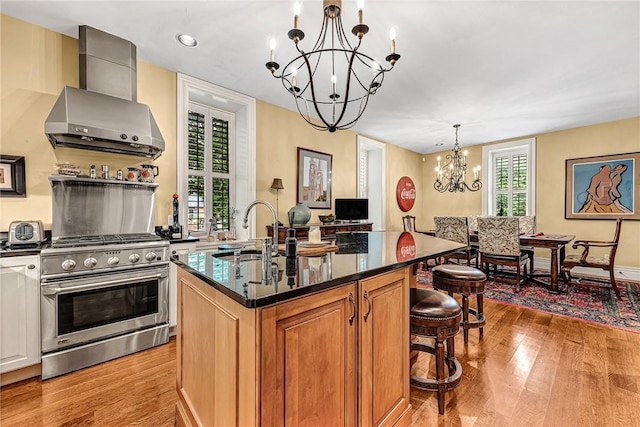 32 Armstrong St, Eureka Springs, AR 72632 - kitchen with high end stove, wall chimney exhaust hood, a chandelier, and light wood-style flooring
