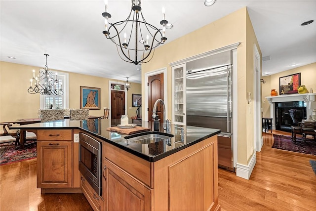 32 Armstrong St, Eureka Springs, AR 72632 - kitchen featuring a chandelier, built in appliances, light wood finished floors, dark stone countertops, and an island with sink
