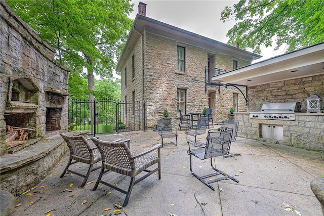 32 Armstrong St, Eureka Springs, AR 72632 - view of patio featuring an outdoor kitchen, an outdoor stone fireplace, and a gate