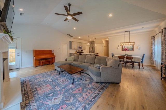 1312 Park St, Lowell, AR 72745 - living area featuring vaulted ceiling, ceiling fan, light wood finished floors, and a chandelier