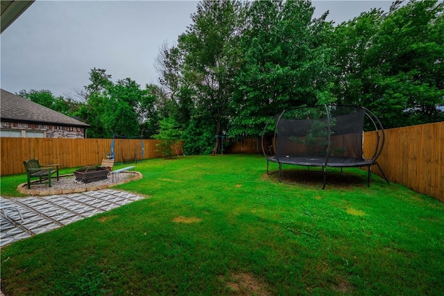 1312 Park St, Lowell, AR 72745 - fenced backyard featuring a trampoline, an outdoor fire pit, and a patio area