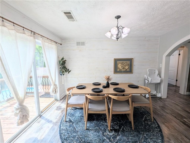 805 S Oak St, Harrison, AR 72601 - dining room with arched walkways, a chandelier, wood finished floors, a textured ceiling, and wooden walls