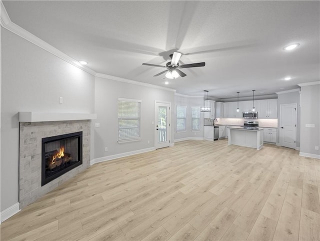 11 Dornoch Cir, Bella Vista, AR 72715 - unfurnished living room featuring crown molding, recessed lighting, a ceiling fan, a lit fireplace, and light wood-style flooring