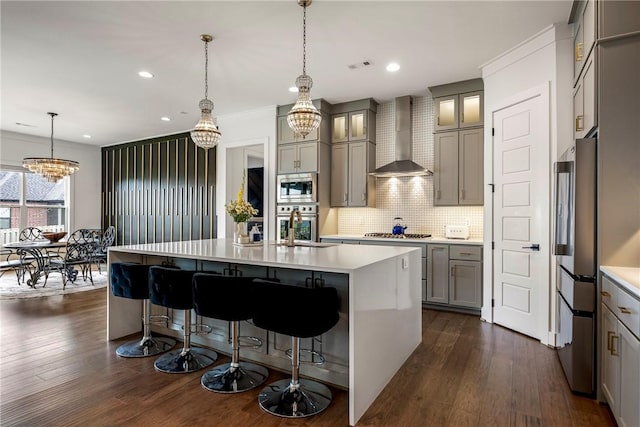 8002 W Claverton St, Rogers, AR 72758 - kitchen with stainless steel appliances, wall chimney exhaust hood, a chandelier, gray cabinets, and dark wood finished floors