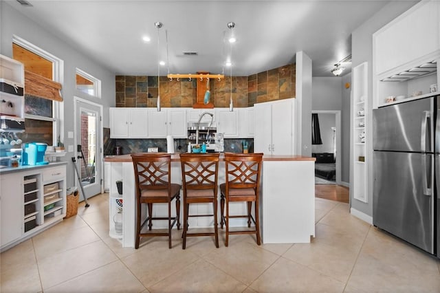 6629 Tall Oaks Loop, Springdale, AR 72762 - kitchen with freestanding refrigerator, white cabinetry, an island with sink, a kitchen bar, and recessed lighting