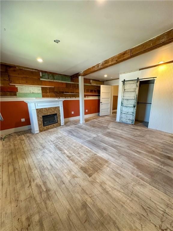 108 Public Sq, Berryville, AR 72616 - unfurnished living room with light wood-style flooring, a tile fireplace, a barn door, and wood walls