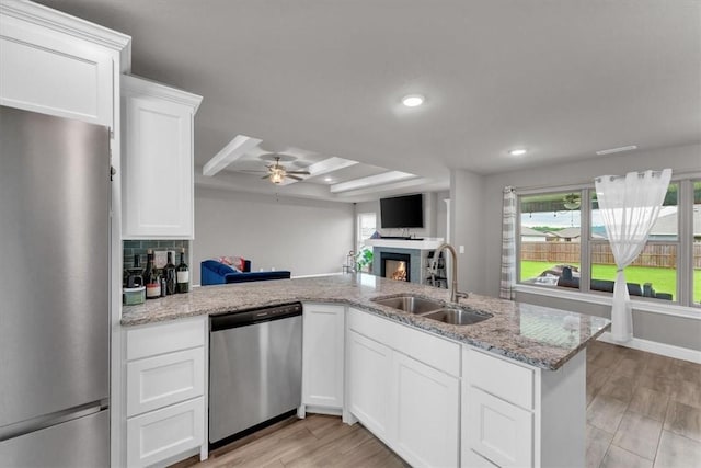 328 N Otoe St, Farmington, AR 72730 - kitchen featuring appliances with stainless steel finishes, a warm lit fireplace, open floor plan, ceiling fan, and light stone countertops