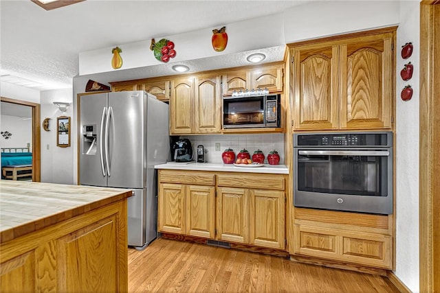 8553 Stoner Ln, Rogers, AR 72756 - kitchen featuring appliances with stainless steel finishes, light wood finished floors, and decorative backsplash