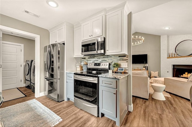 1314 N Fieldstone Ave, Fayetteville, AR 72704 - kitchen featuring stainless steel appliances, washer and dryer, open floor plan, tasteful backsplash, and light wood-style floors