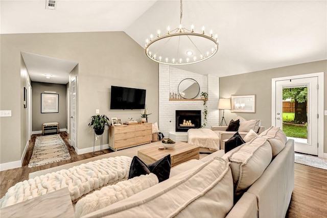1314 N Fieldstone Ave, Fayetteville, AR 72704 - living area with vaulted ceiling, a chandelier, wood finished floors, and a brick fireplace