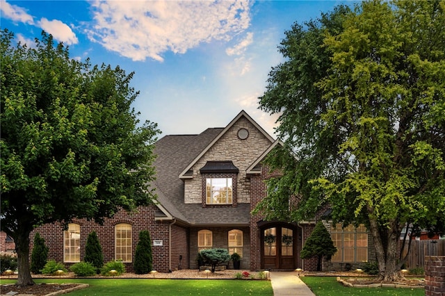 501 SE Fullerton St, Bentonville, AR 72712 - view of front of house featuring brick siding, a shingled roof, a front yard, and stone siding