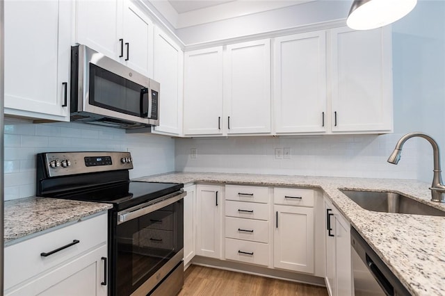 315 E 11th St, Fayetteville, AR 72701 - kitchen featuring appliances with stainless steel finishes, white cabinetry, light wood-type flooring, and tasteful backsplash