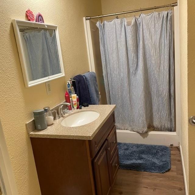 4841 Business Highway 412, Huntsville, AR 72740 - bathroom with vanity, wood finished floors, shower / bath combo with shower curtain, and a textured wall