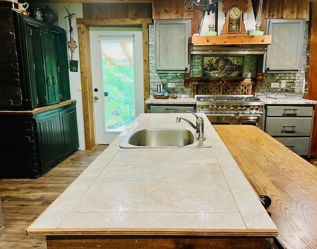14163 Low Gap Wc 100 Rd, West Fork, AR 72774 - kitchen featuring range with two ovens, tile counters, wood finished floors, tasteful backsplash, and premium range hood