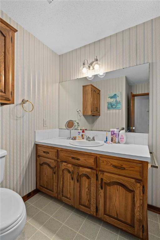 319 Belle Ave, Alma, AR 72921 - bathroom featuring wallpapered walls, vanity, a textured ceiling, and tile patterned flooring