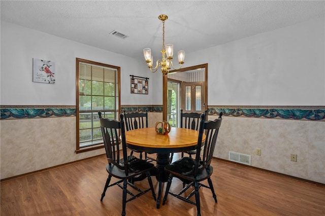 319 Belle Ave, Alma, AR 72921 - dining area with a chandelier, wood finished floors, a wainscoted wall, wallpapered walls, and a textured ceiling