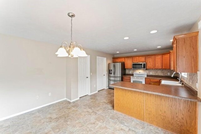 150 Cedar Wood Ave, Branson, MO 65616 - kitchen featuring appliances with stainless steel finishes, brown cabinets, a chandelier, backsplash, and a peninsula