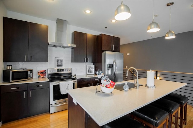 3901 W 5th St, Fayetteville, AR 72701 - kitchen with appliances with stainless steel finishes, wall chimney range hood, light countertops, a kitchen bar, and light wood-style floors