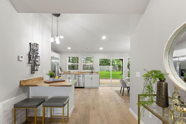 802 Hinshaw Dr, Springdale, AR 72762 - kitchen with stainless steel appliances, butcher block counters, a peninsula, light wood finished floors, and white cabinetry