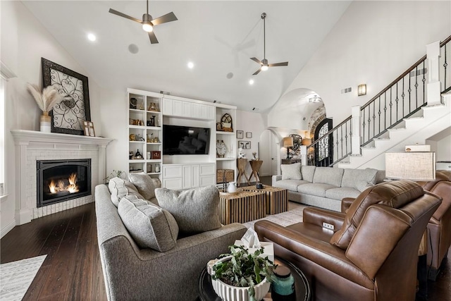 11267 Walters Rd, Bentonville, AR 72712 - living area featuring ceiling fan, arched walkways, a glass covered fireplace, high vaulted ceiling, and stairway