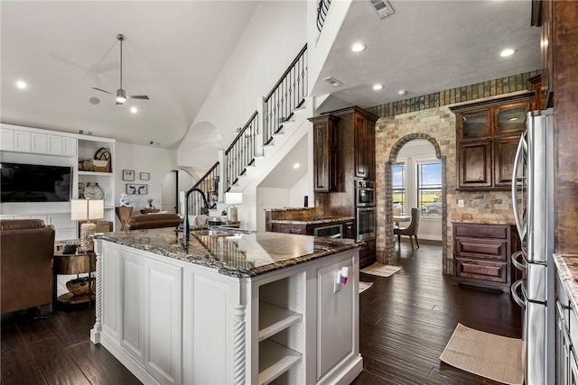 11267 Walters Rd, Bentonville, AR 72712 - kitchen featuring appliances with stainless steel finishes, arched walkways, ceiling fan, dark stone counters, and open shelves