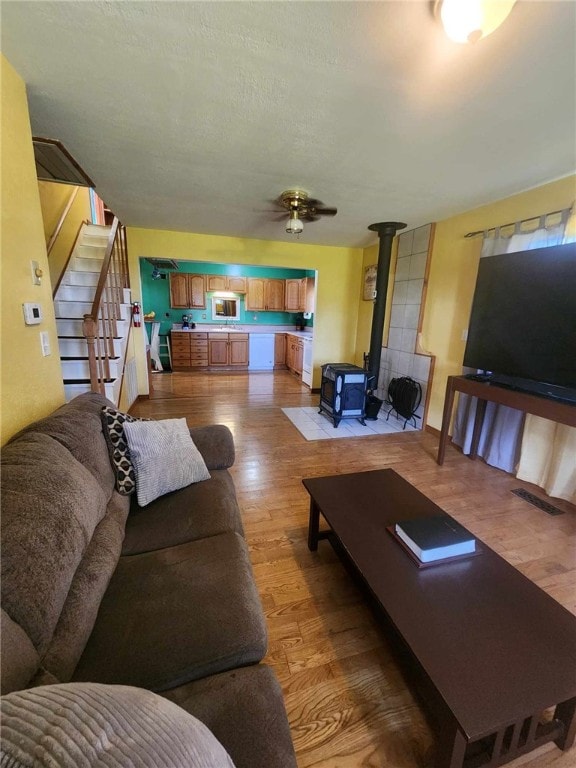46 Hathcoat Rd, Harrison, AR 72601 - living room featuring a wood stove, light wood-style flooring, stairway, and ceiling fan