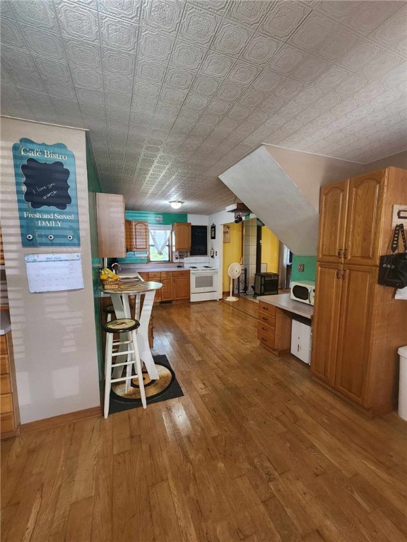 46 Hathcoat Rd, Harrison, AR 72601 - kitchen with white appliances, wood-type flooring, an ornate ceiling, brown cabinetry, and light countertops