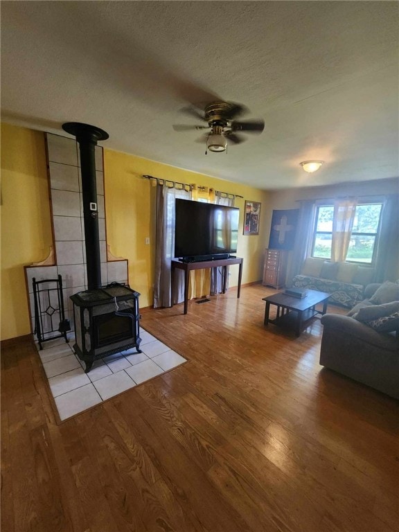 46 Hathcoat Rd, Harrison, AR 72601 - living area featuring light wood finished floors, a wood stove, ceiling fan, and a textured ceiling
