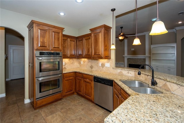 3402 Crosswinds Blvd, Bentonville, AR 72713 - kitchen featuring stainless steel appliances, ceiling fan, brown cabinetry, arched walkways, and backsplash