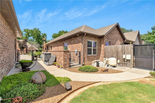 460 Viney Grove Rd, Prairie Grove, AR 72753 - view of home's exterior with a gate, brick siding, and roof with shingles