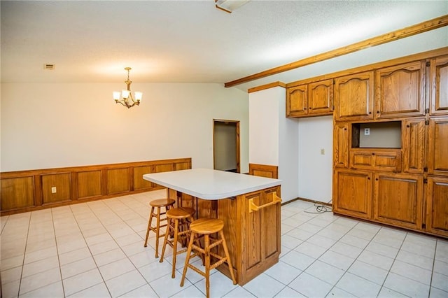 5315 Walden St, Lowell, AR 72745 - kitchen featuring brown cabinets, a chandelier, lofted ceiling, light countertops, and a kitchen breakfast bar