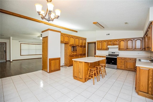 5315 Walden St, Lowell, AR 72745 - kitchen with electric range, vaulted ceiling, brown cabinets, a textured ceiling, and under cabinet range hood