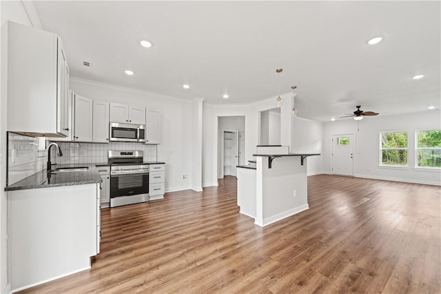 2 Wendike Ln, Bella Vista, AR 72715 - kitchen featuring appliances with stainless steel finishes, a ceiling fan, open floor plan, a kitchen breakfast bar, and backsplash