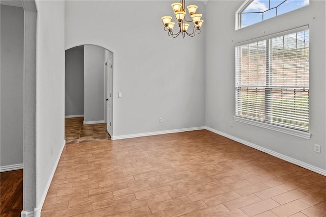 4788 Soapstone Dr, Fayetteville, AR 72704 - unfurnished room with arched walkways, a chandelier, light wood-type flooring, and a high ceiling