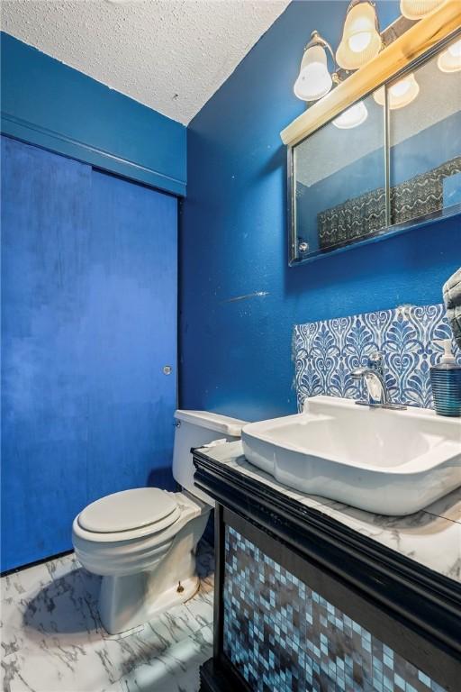 2000 W Wood St, Rogers, AR 72756 - half bath with vanity, a textured ceiling, and marble finish flooring