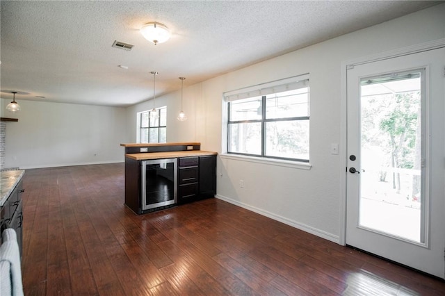 707 Turtle Creek Dr, Rogers, AR 72756 - kitchen with wine cooler, dark wood-type flooring, a peninsula, a textured ceiling, and hanging light fixtures