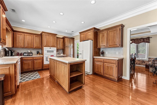 8270 Titleist Cir, Rogers, AR 72756 - kitchen with white appliances, tile countertops, a center island, brown cabinetry, and light wood-type flooring