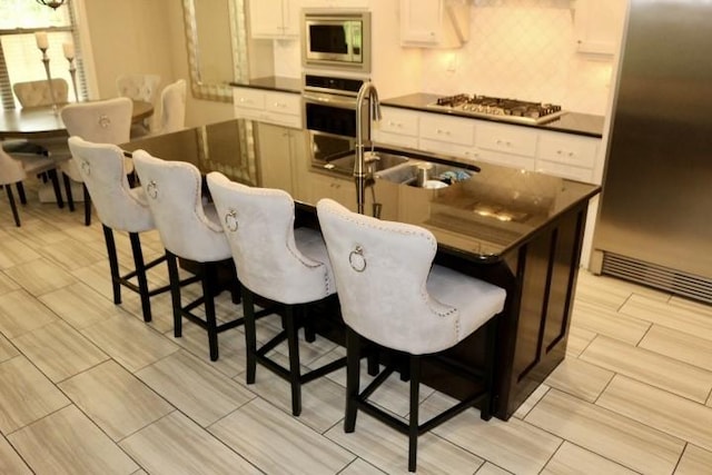 1730 Helen Ln, Bentonville, AR 72713 - kitchen featuring appliances with stainless steel finishes, dark countertops, decorative backsplash, and white cabinets