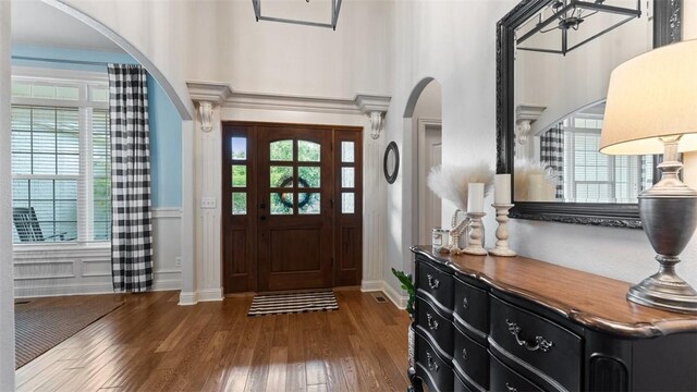 4903 S Inglewood Rd, Rogers, AR 72758 - foyer entrance with arched walkways, wood finished floors, plenty of natural light, a wainscoted wall, and a towering ceiling