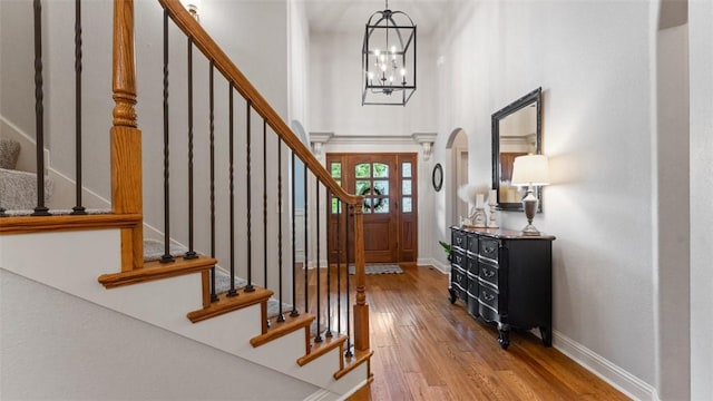 4903 S Inglewood Rd, Rogers, AR 72758 - entryway featuring wood finished floors, stairs, a chandelier, arched walkways, and a towering ceiling